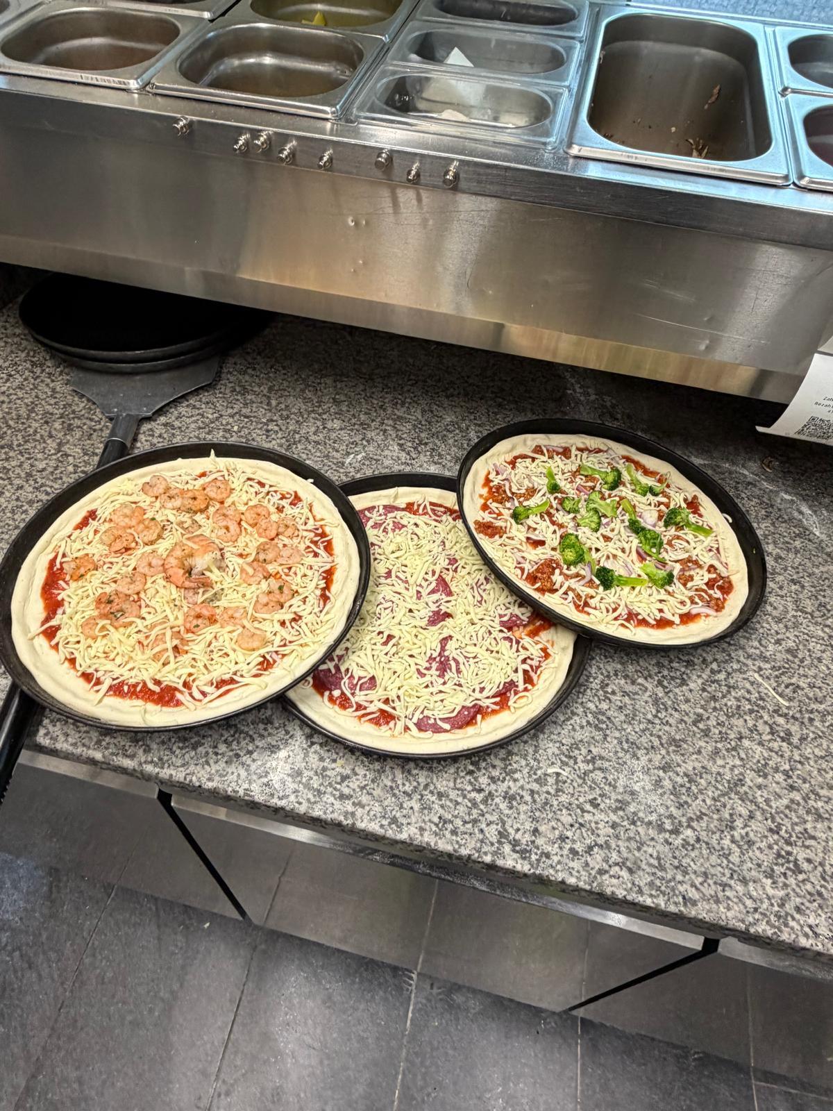 Frisch belegte Pizzen in der offenen Küche